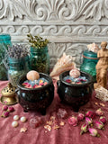 Hand-poured Aphrodite ritual cauldron candle in slate soy wax with aquamarine crystals, seashells & rose petals. Perfect for self-love rituals. Order today!